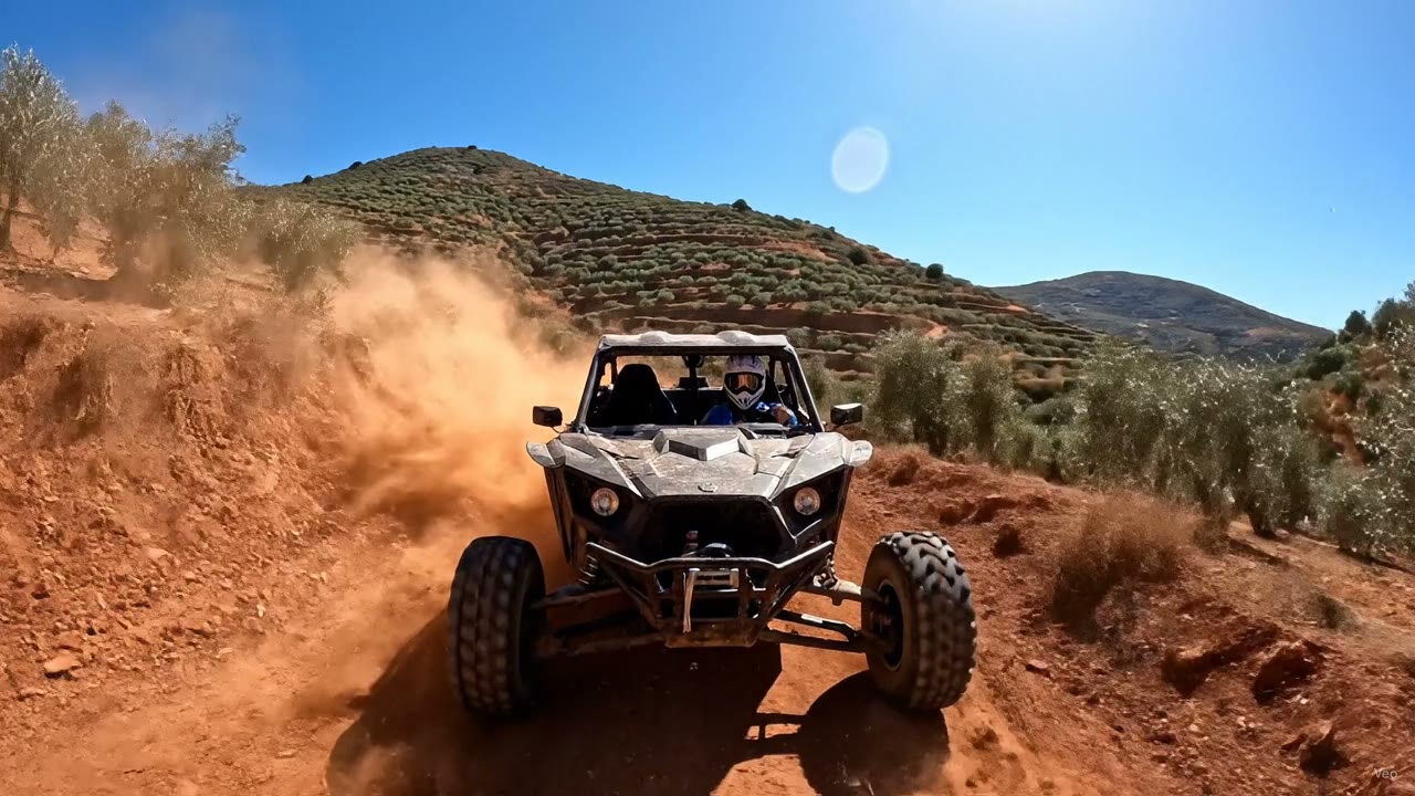 Buggy met stofwolk op een rood bergpad tussen de olijfterrassen