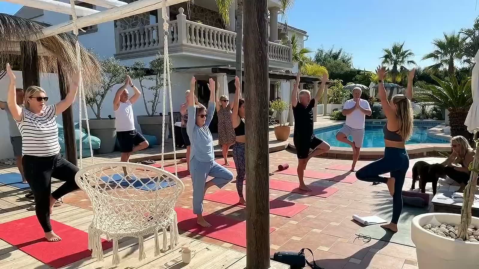 Yogagroep in houding op het deck bij het zwembad, met uitzicht over de vallei