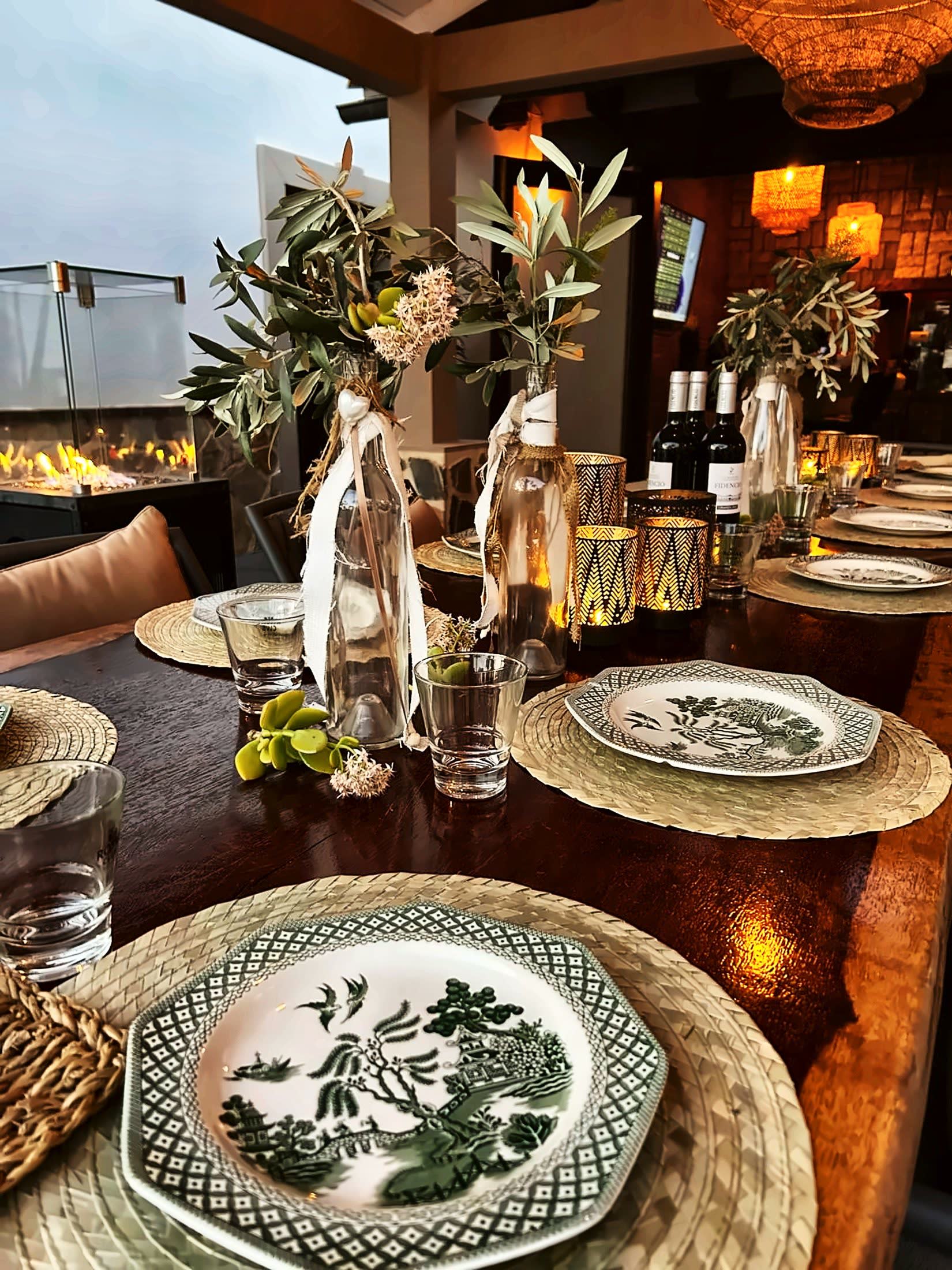 Tafeldetail met groen servies, olijftakjes en kaarslicht