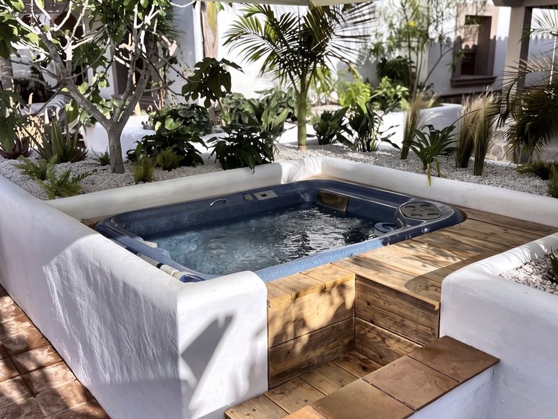 De verzonken jacuzzi tussen de beplanting, met houten dek